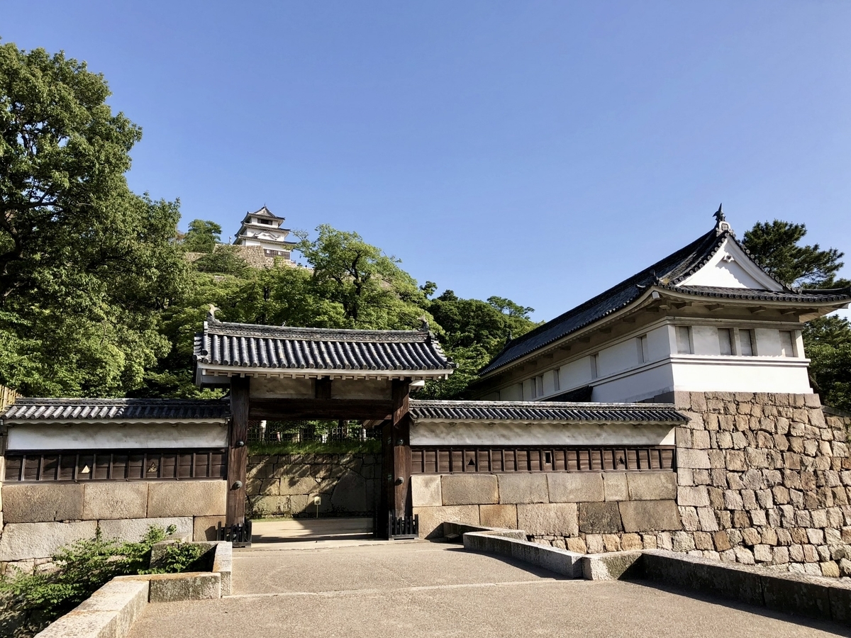 Daytime view of Marugame Castle’s Otemon Gate and stone walls, with the keep visible in the background.