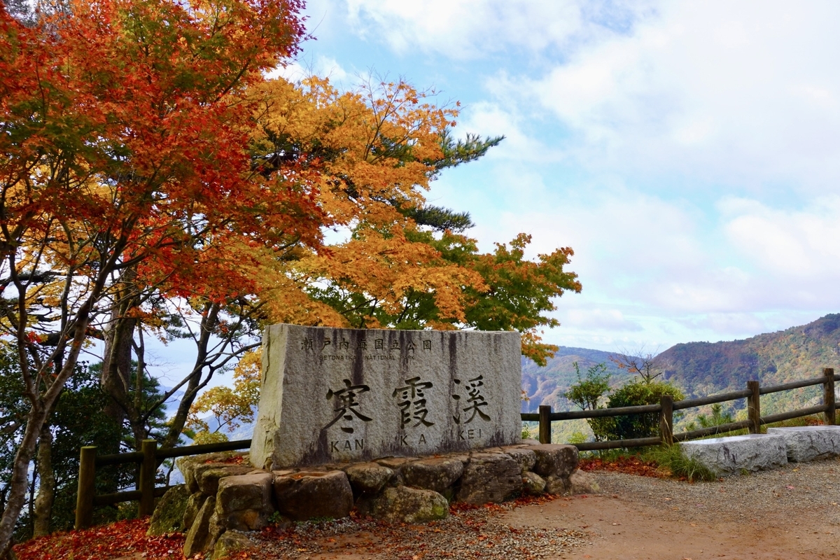 Monumento de piedra de Kankakei rodeado de follaje otoñal y cielo azul