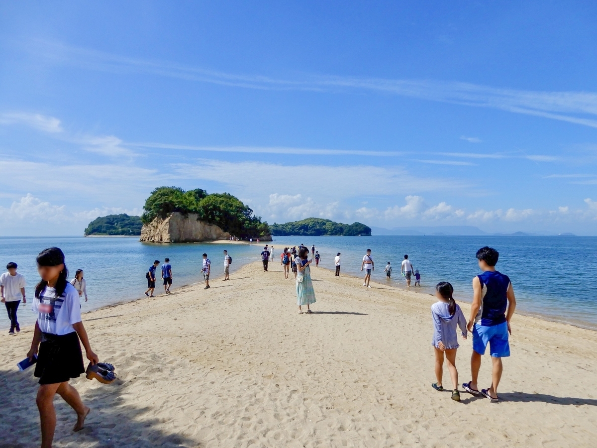 Many visitors walking along the Angel Road sand path at low tide