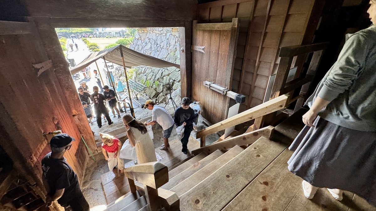 Visitors removing shoes at the keep entrance, wooden stairs in background