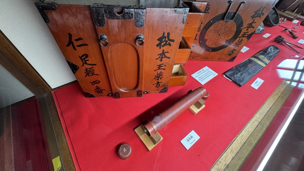 Exhibit of wooden tags and armor on red platform in Tatsumi Turret