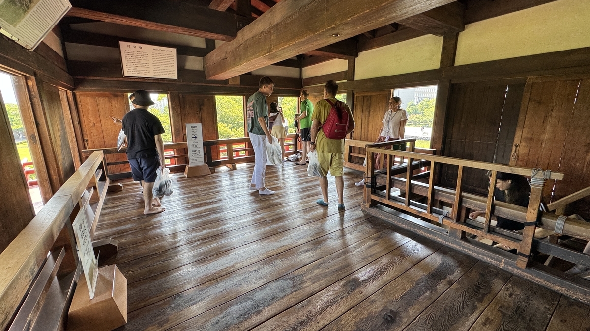 Visitors walking along vermilion balcony inside Moon-Viewing Turret