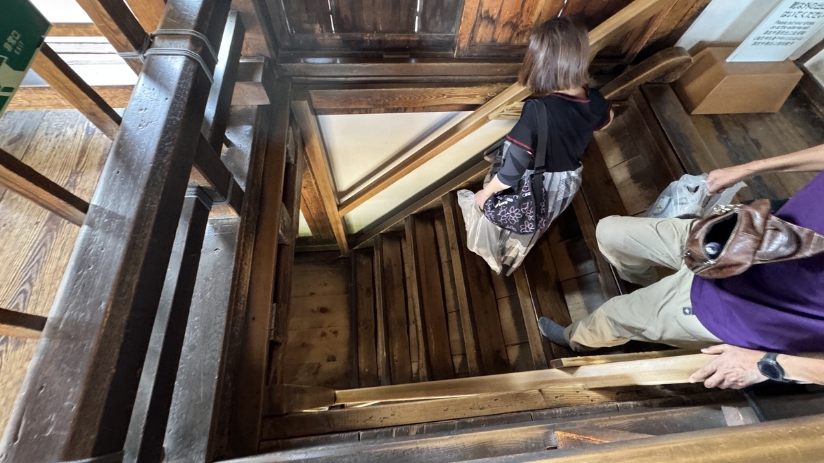 Visitors descending wooden stairs leading to the exit of Matsumoto Castle keep