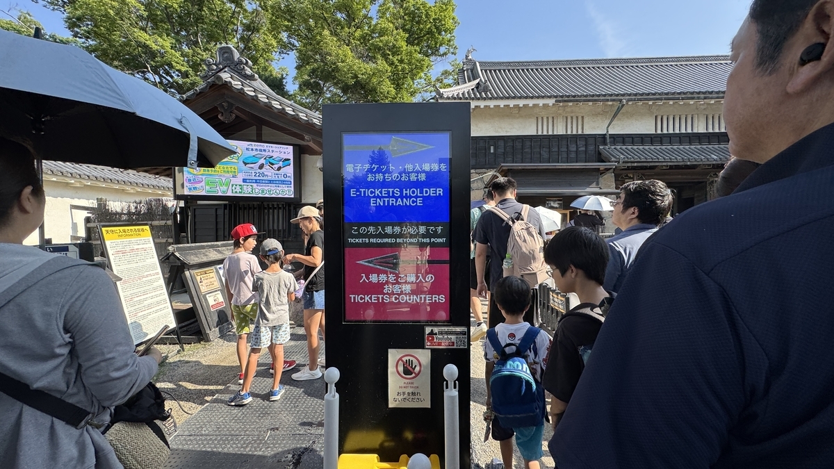 Visitors queuing to buy Matsumoto Castle tickets and guidance signage