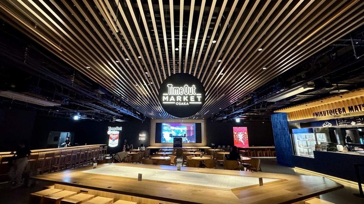 Interior de Timeout Market Osaka con un gran logo y techo de madera en el food hall