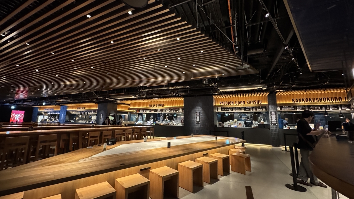 Espacio ordenado con mesas y sillas de madera en Timeout Market Osaka