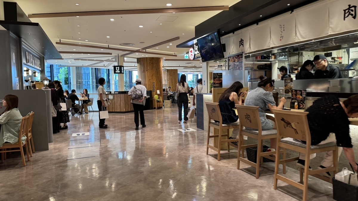 Hanshin Dai-Shokudo food hall area. Multiple stores line the space where people enjoy meals in front of open kitchens.