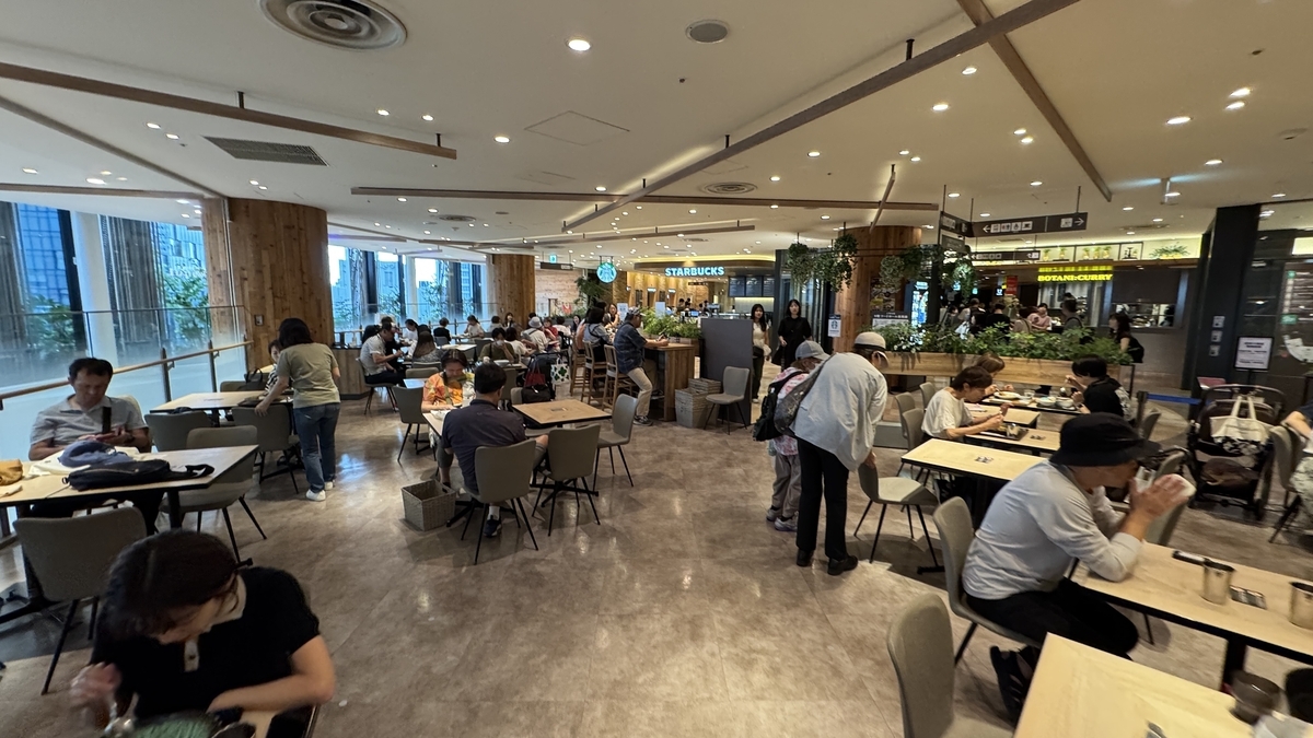 Spacious seating area of Hanshin Dai-Shokudo food hall, filled with customers enjoying their meals during lunchtime.