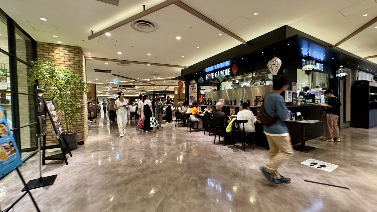 Corridor of Hanshin Dai-Shokudo lined with restaurants. Shoppers walk through the open, lively space.