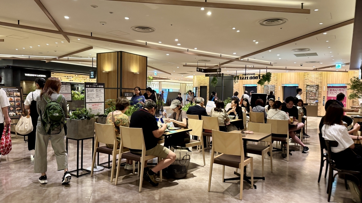 Dining area of Hanshin Dai-Shokudo with many people enjoying meals under bright lighting.