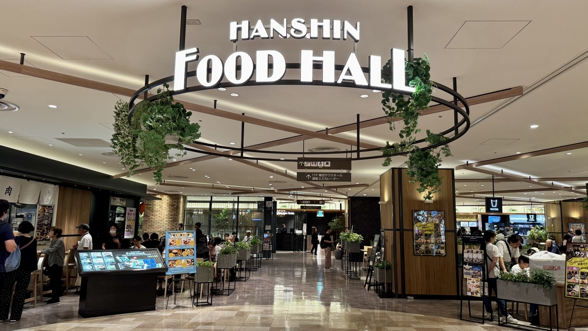Entrance sign of Hanshin Dai-Shokudo FOOD HALL decorated with greenery, leading into the vibrant dining area.