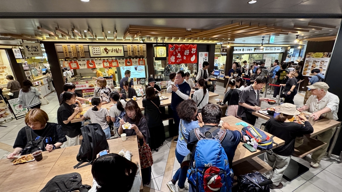 スナックパーク中央の立ち食いカウンター。混雑する店内で食事を楽しむ人々
