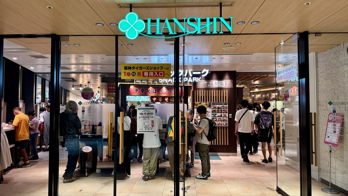 阪神梅田本店の地上入口。スナックパークへの案内看板と多くの来店客が写る