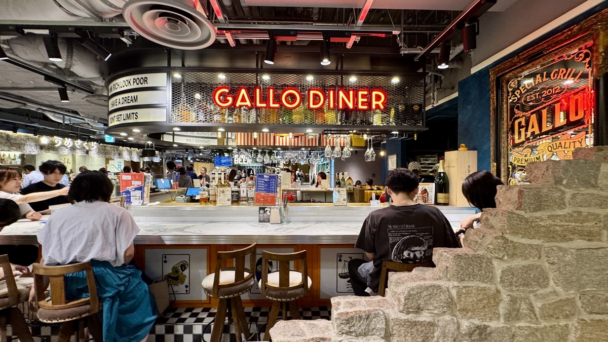 한신 바르 요코초 안의 GALLO Diner. 네온 간판이 빛나고 고기 요리와 드링크로 활기가 넘친다.