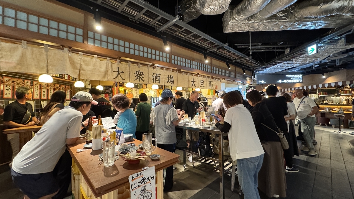 にぎやかな立ち飲みスペースで客が集うKITTE大阪うめよこの夜の雰囲気