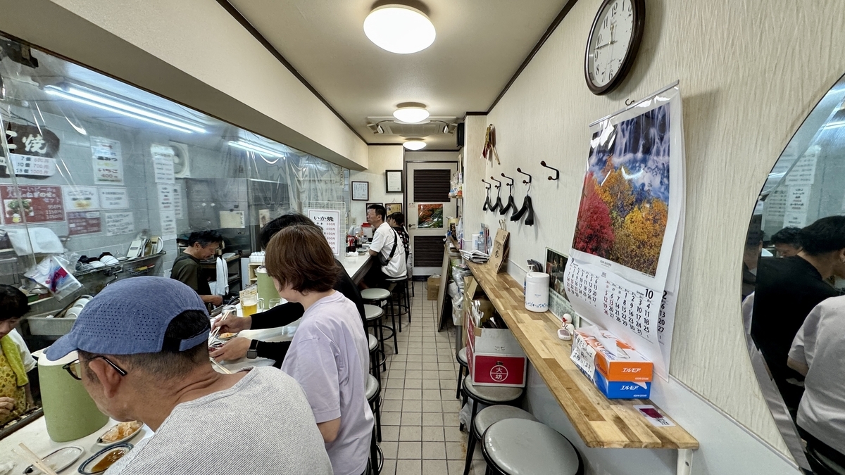 Interior view of Ichifuku with customers at the counter and staff grilling takoyaki in the back