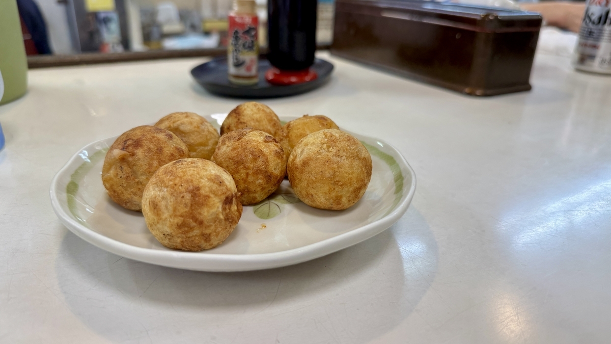 Seven freshly grilled takoyaki balls on a plate with a beautiful golden color