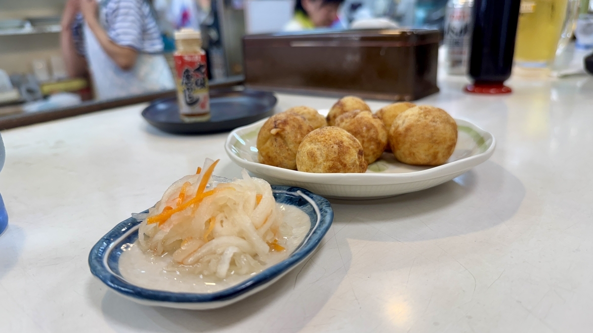 Plate of takoyaki and namasu on the counter, creating a calm, classic atmosphere