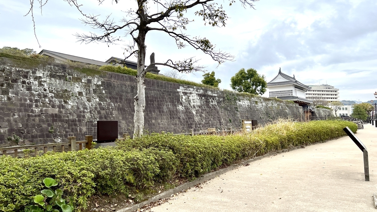 Quiet pathway lined with stone walls and moats at Tsurumaru Castle Ruins