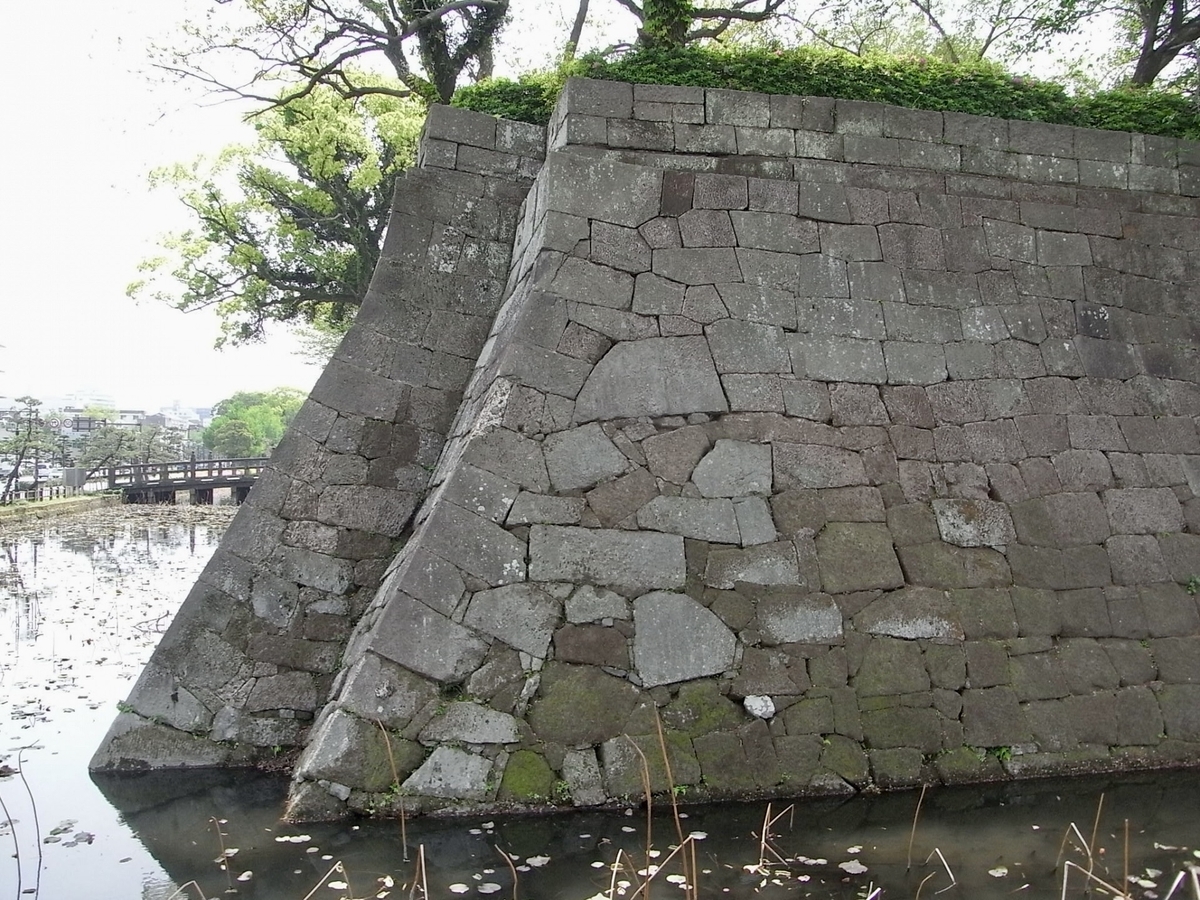 Tranquil scene of stone walls reflected in the green surface of the castle moat