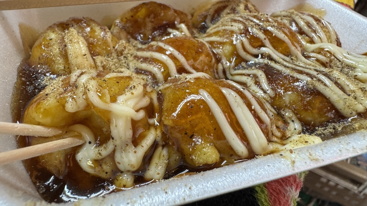 Moment of lifting a melting-soft takoyaki with chopsticks