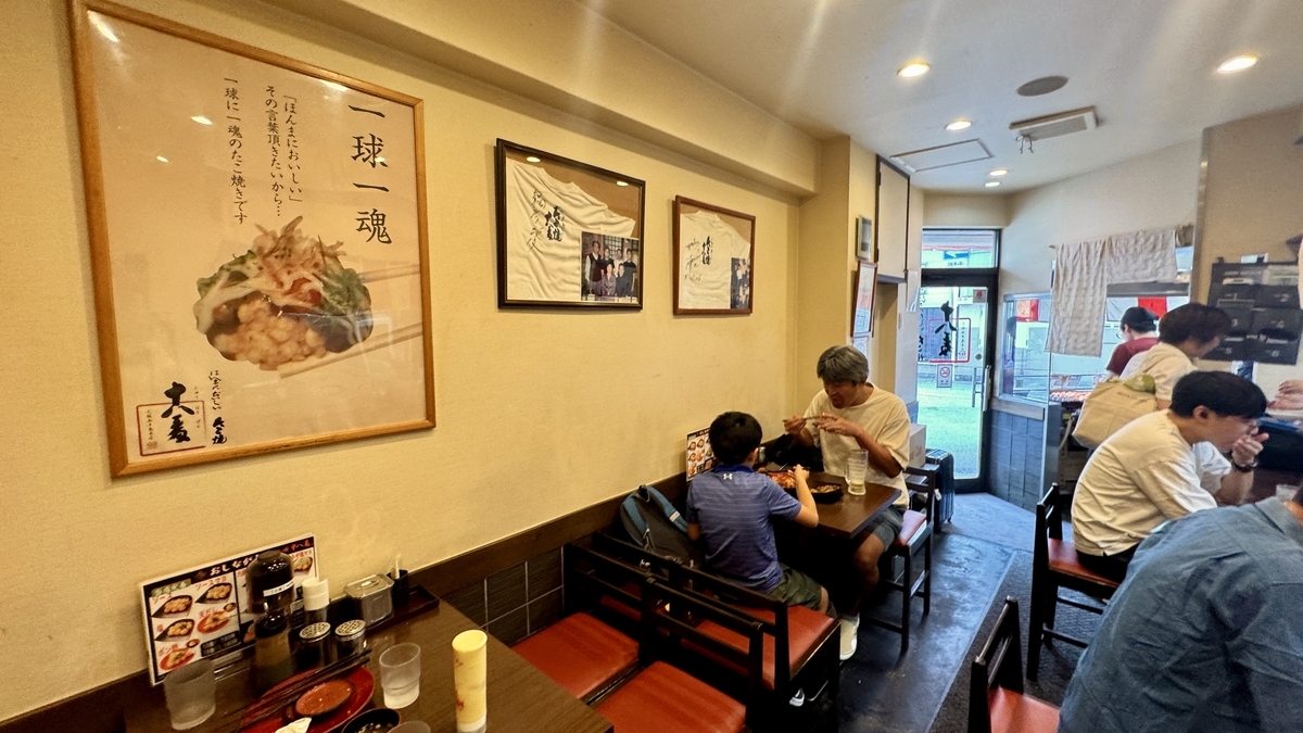 테이블석에서 식사를 즐기는 손님들이 있는 타코야키 주하치반 니시나카지마 본점의 모습