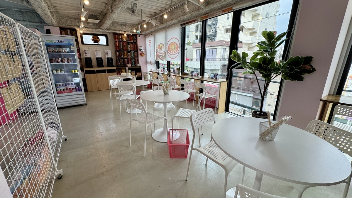 大きな窓に面した白い丸テーブルとピンクの内装 明るい店内の雰囲気