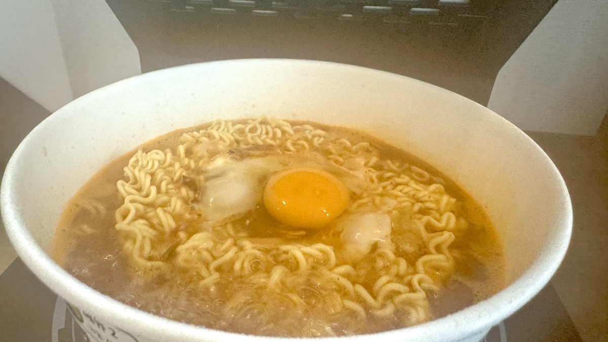 熱々のスープに落とされた卵が白く固まり始めた調理中の様子