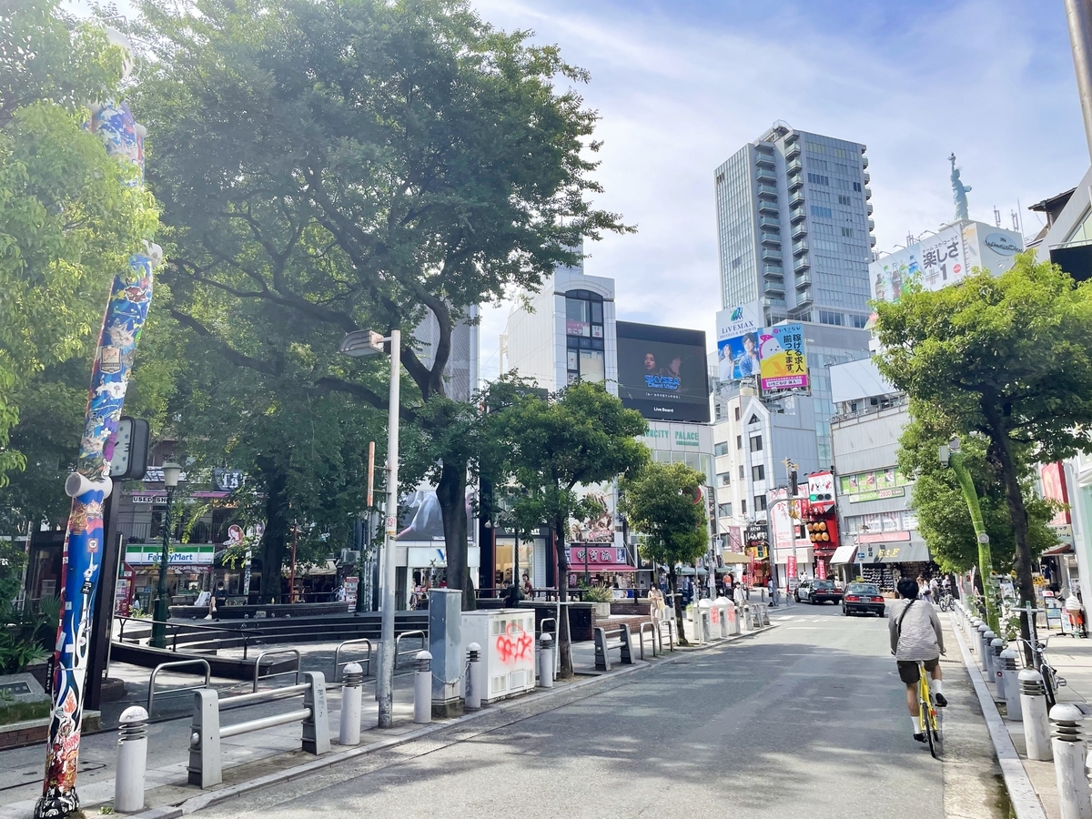 บรรยากาศถนนในอเมริกามูระช่วงเวลากลางวัน มีต้นไม้และตึกเรียงรายรอบ Sankaku Park
