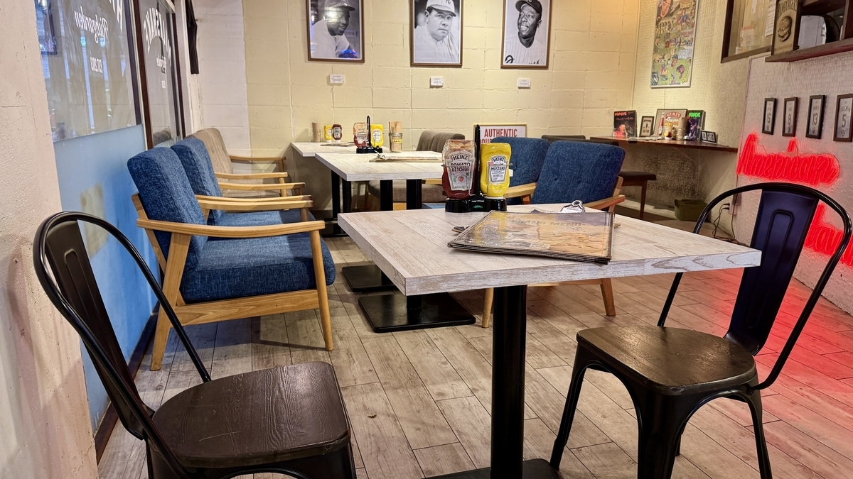 โซฟาและโต๊ะในโซนที่นั่งของ RICH GARDEN สาขาชินไซบาชิ พร้อมภาพถ่ายแนวพอร์ตเทรตบนผนัง