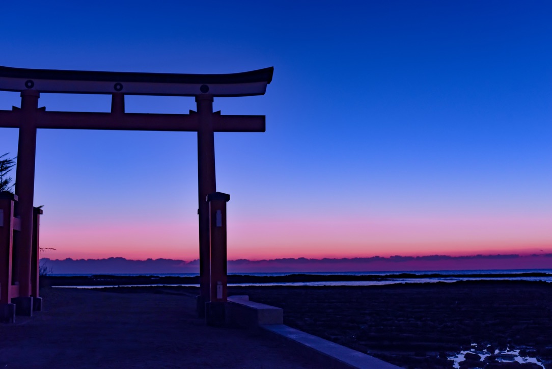夜明けの空を背景に赤い鳥居がシルエットで浮かぶ幻想的な青島神社の景色