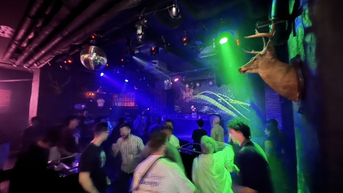 Visitantes bailando en el piso de PURE OSAKA bajo luces coloridas