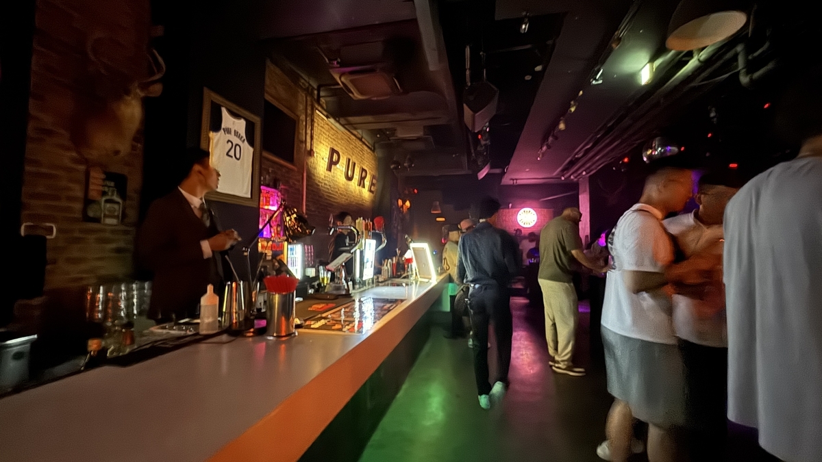 Zona de entrada y mostrador iluminados en PURE OSAKA con visitantes pasando