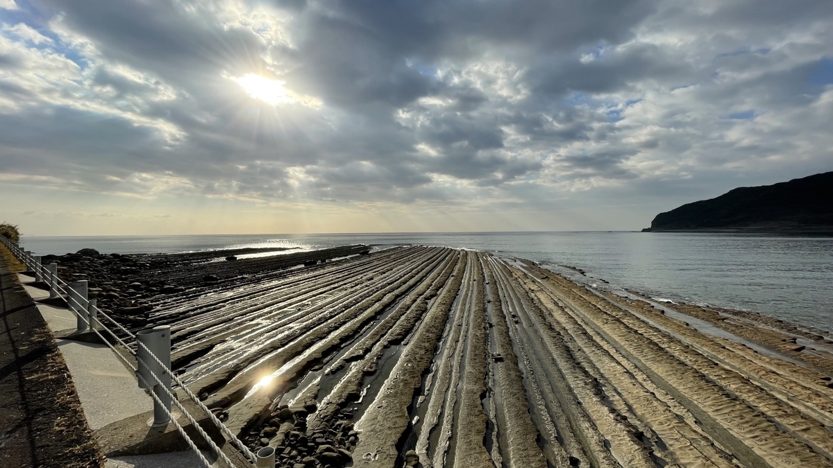 夕日を受けて輝く鬼の洗濯板の岩肌と海