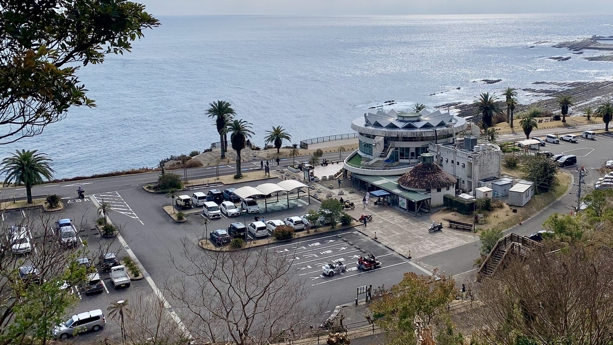 木々に囲まれた広い駐車場に停車する車とバイクの様子