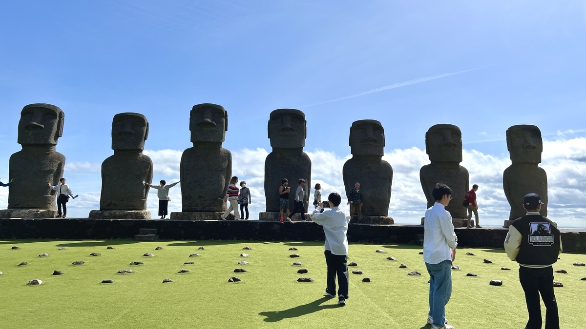 芝生の上に整然と並んだモアイ像と周囲の観光客の様子
