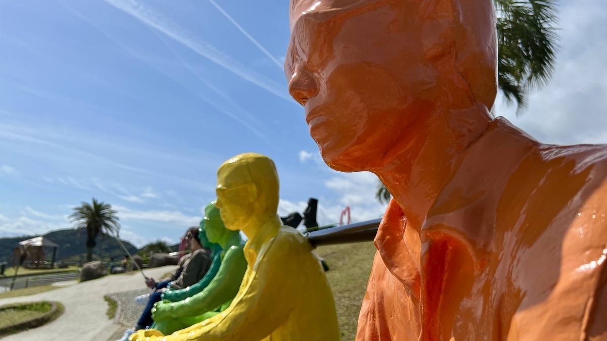 色鮮やかな七体のヴォワイヤン像が芝生の上に並び太平洋を見つめる様子