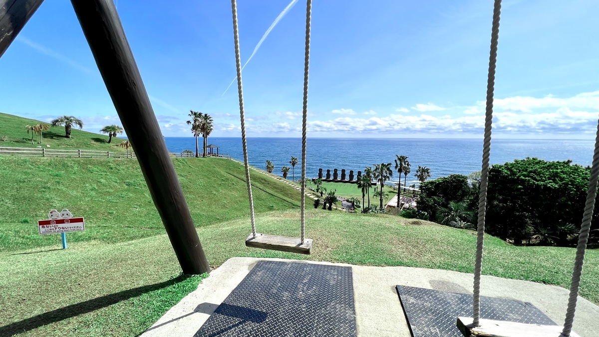 青空と海を背景にしたブランコの座面とロープの近景
