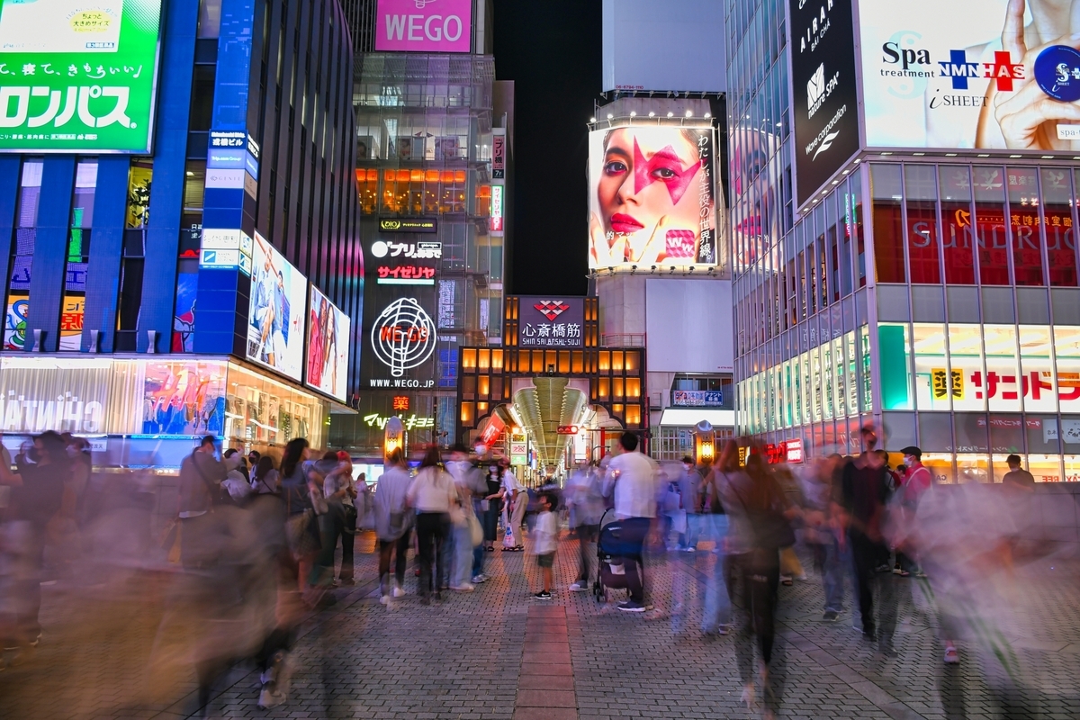 Ambiente nocturno animado de Shinsaibashi con letreros de neón iluminando las calles