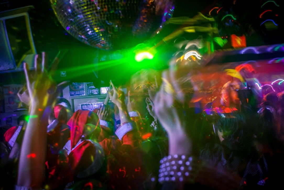 Pista de baile iluminada con luces coloridas y multitud animada