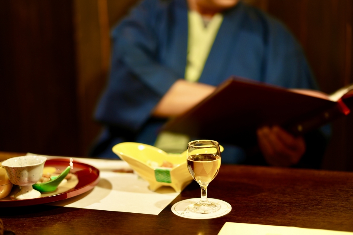 居酒屋の座敷で徳利と料理を前に食事を楽しむ様子