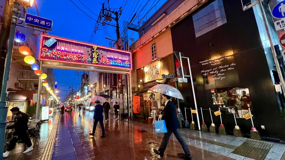 Neon lights illuminating the Nishitachi entertainment district on a rainy night