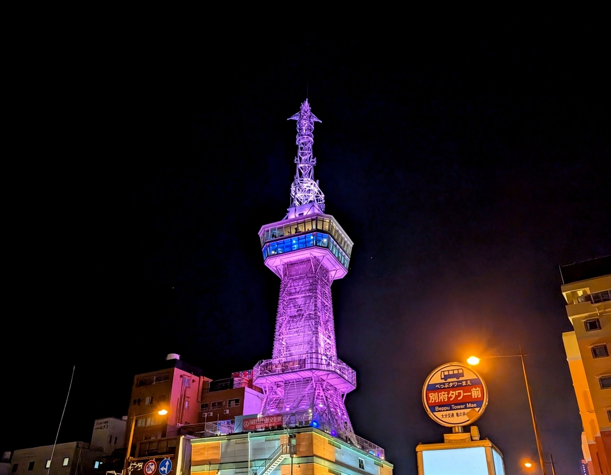 보라색으로 라이트업된 야간 벳푸타워와 버스정류장 표지판