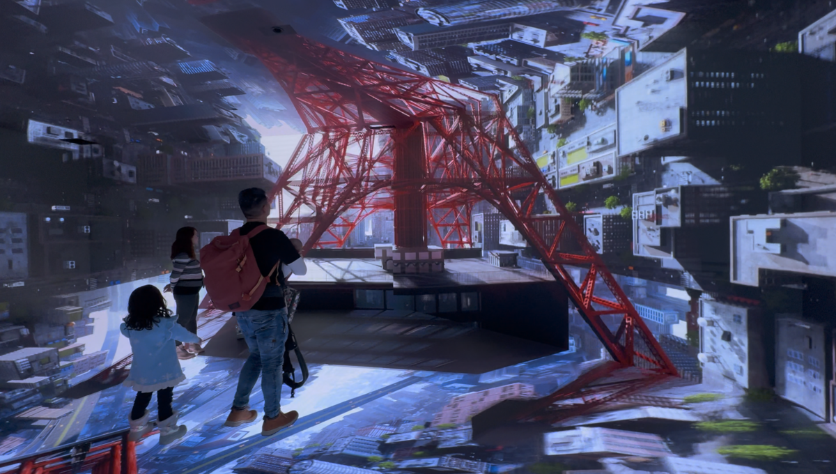 東京タワーの鉄骨を見上げる映像に見入る家族連れの後ろ姿