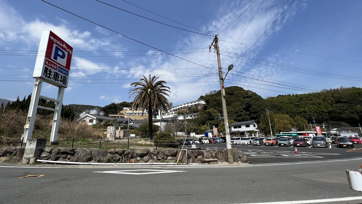 鬼山地獄の駐車場看板と広い駐車スペースが見える道路沿いの風景