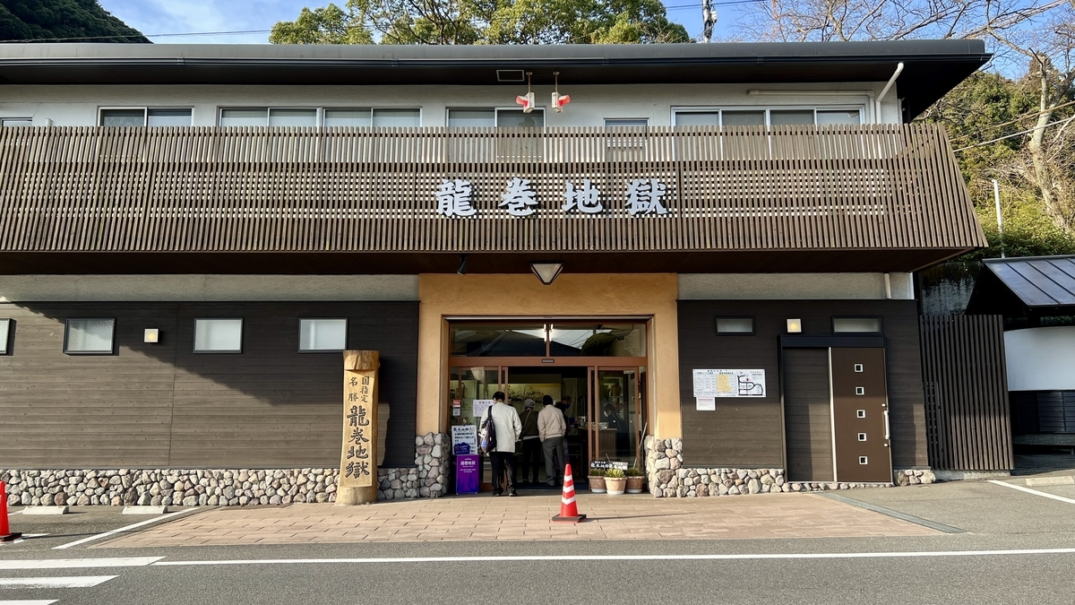 龍巻地獄の入口建物の外観で木格子の壁に施設名の看板が掲げられ来場者が出入りしている様子