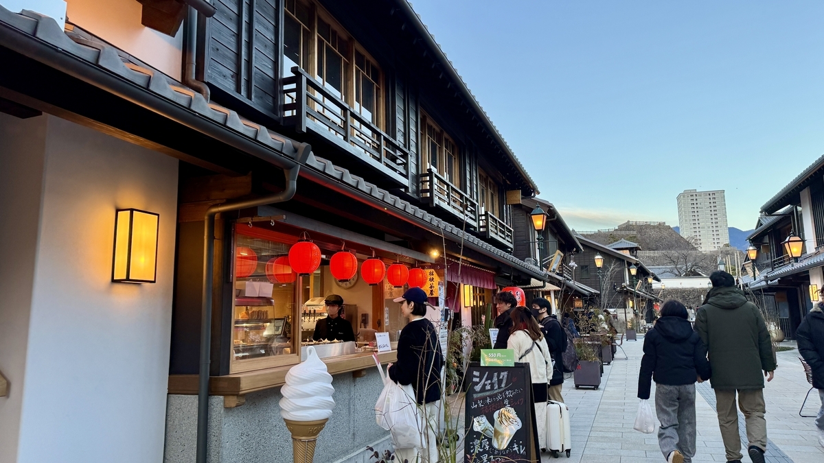 빨간 제등이 켜진 야타이 풍 점포에서 쇼핑하는 사람들, 소프트 아이스크림 간판이 있는 저녁 거리