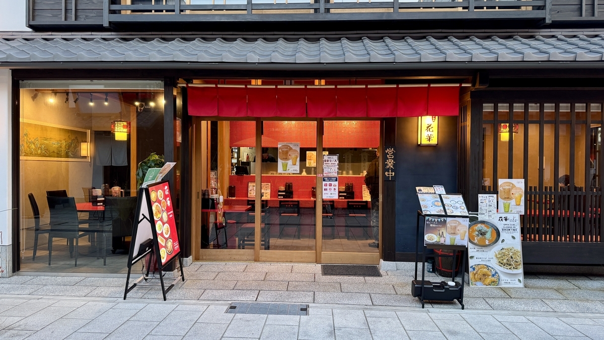 빨간 노렌이 돋보이는 마치야 음식점 정면, 메뉴 간판과 점내 행등이 보이는 저녁 풍경