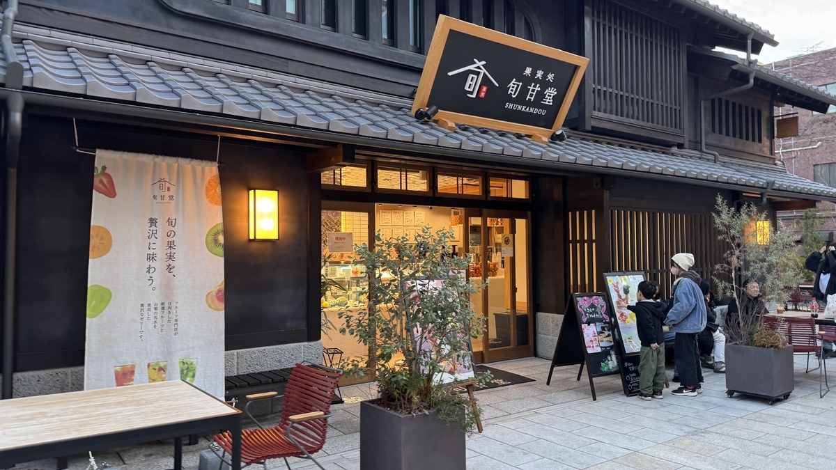 가지쇼 슌칸도 점포 앞, 제철 과일 스위츠 간판과 시음 메뉴를 올려다보는 부모와 아이