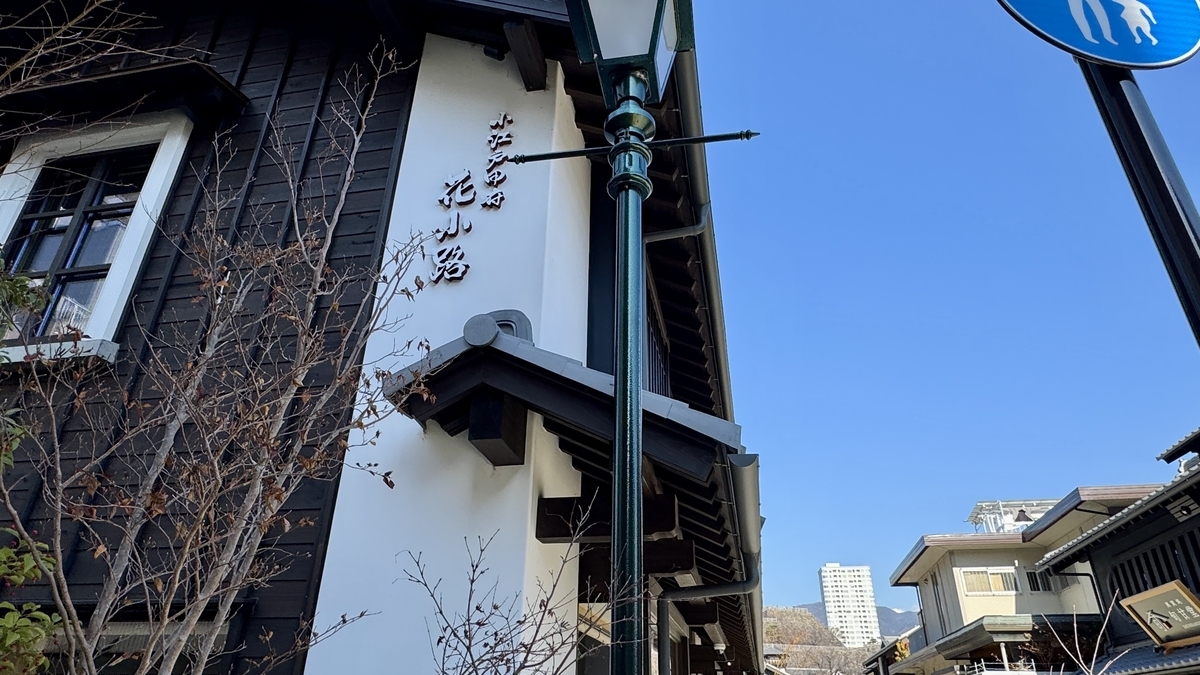 흰 벽 마치야에 걸린 고에도 고후 하나코지 세로 간판, 푸른 하늘에 가로등과 기와지붕이 비치는 풍경